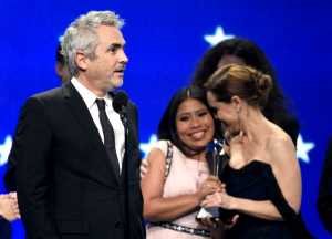 Alfonso Cuaron, from left, accepts the award for best picture for "Roma" as Yalitza Aparicio and Marina De Tavira react at the 24th annual Critics' Choice Awards on Sunday, Jan. 13, 2019, at the Barker Hangar in Santa Monica, Calif. (Photo by Chris Pizzello/Invision/AP)